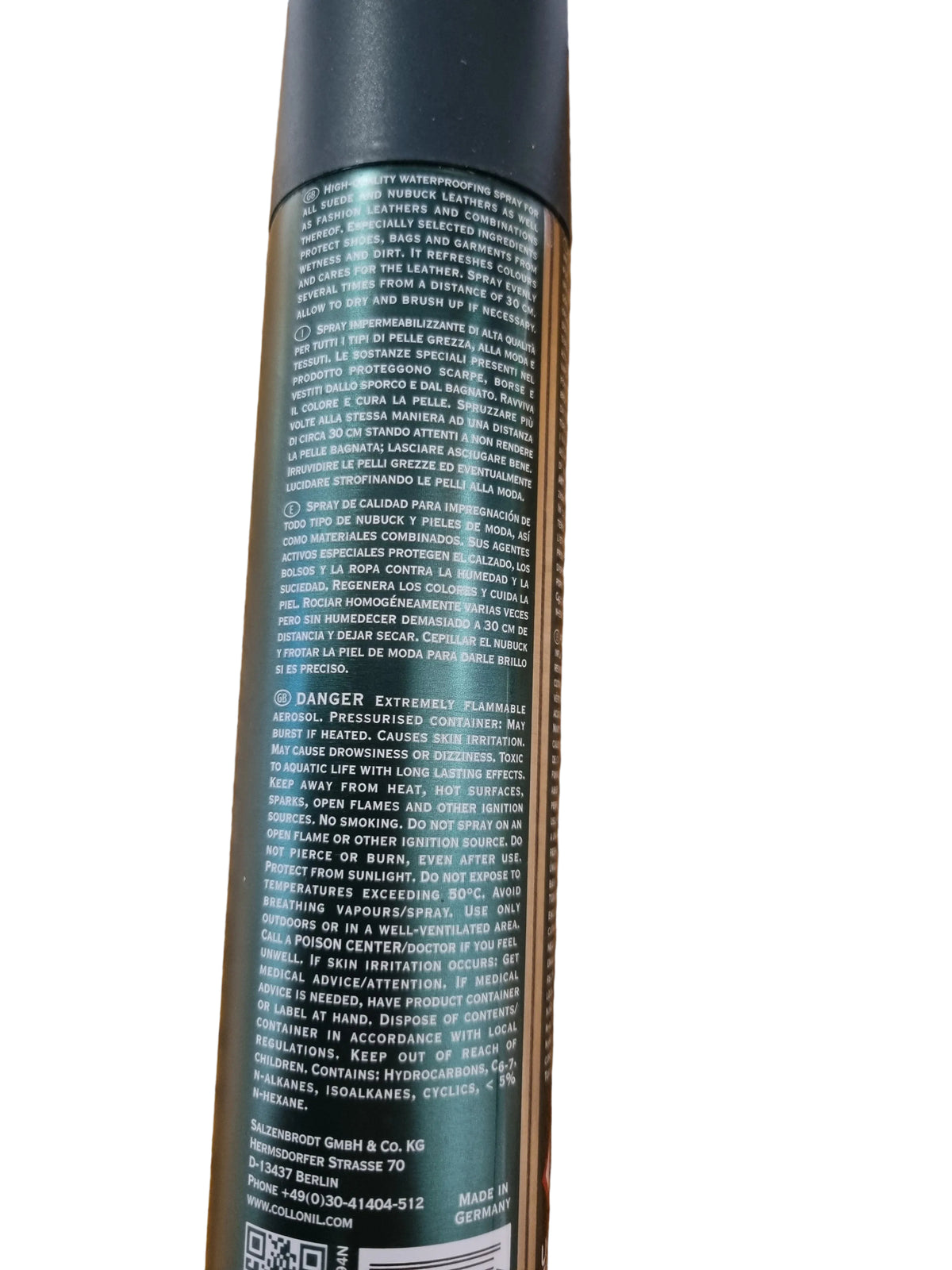 A close-up of the back of a dark green spray can with dense white text, photographed on a wooden tabletop.