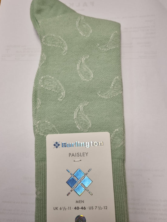 A light sage green knit sock with a white paisley pattern, featuring a white paper tag attached that reads 'Burlington Paisley' and shows size information for men.