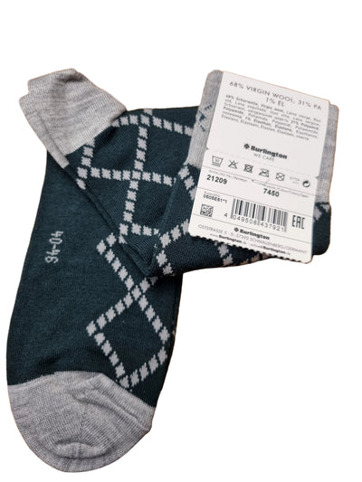 A pair of dark teal argyle socks with gray toes and heels, shown with a white product tag on a wooden surface. The tag shows the brand Burlington.