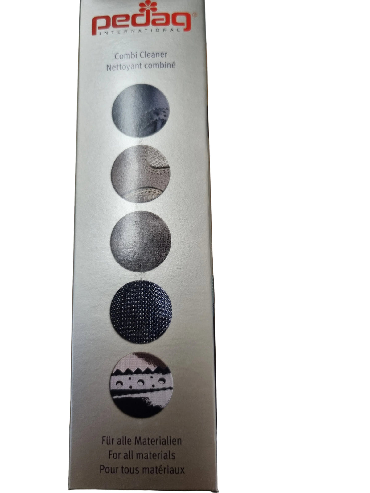 A tall rectangular Pedag Combi Cleaner box standing on a wooden tabletop. The packaging is metallic silver with red Pedag branding at the top and five circular material-use icons printed vertically in dark gray and black.